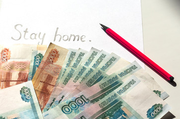 The text stay at home on white paper and Russian banknotes. Concept of quarantine coronavirus