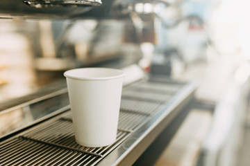 A cardboard Cup for coffee with you. White coffee Cup in the coffee machine.