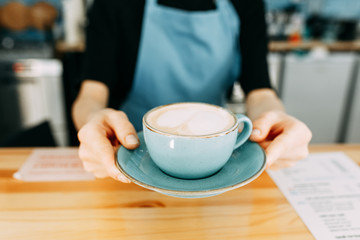 She holds it out and gives it to me in a saucer. Take coffee with you at the coffee shop. Coffee mug in the hands of the Barista.
