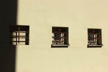 Three small windows built in plaster wall. Symmetry in building facade.