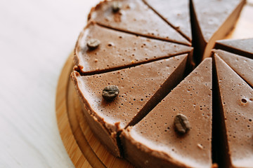 Cheesecake cut into slices in a coffee shop. Chocolate cake on a wooden Board.