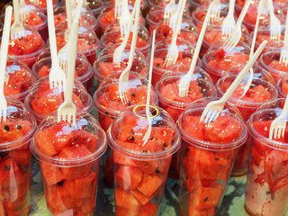 Watermelon cubes in glasses. Portions of watermelon on the counter.