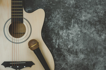 Table top view of music instrument tools concept background.Flat lay of sign to sing for musician or party equipment.Guitar with microphone on modern grey cement.copy space for creative design.