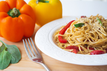 Chinese egg noodles in soy sauce with colorful bell peppers, greens and spring onions with sesame seeds sprinkled on top