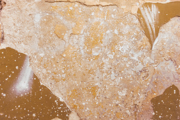 The old peeling plaster wall is beige and brown