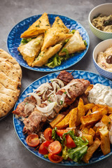 Souvlaki served with fried potatoes, tzatziki dip and pita bread, greek cuisine.