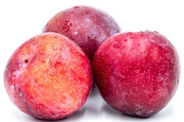 Three ripe red round plums isolated
