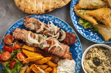 Souvlaki served with fried potatoes, tzatziki dip and pita bread, greek cuisine.