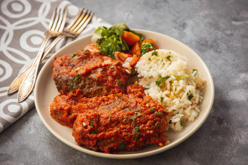 Minced meat cutlets in tomato sauce, served with rice, bifteki-greek cuisine.