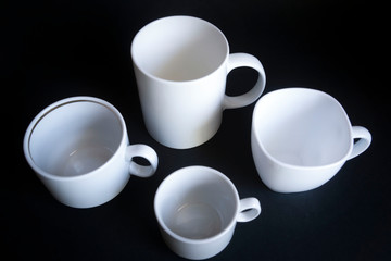 Obraz na płótnie Canvas Large, medium, small cups for coffee against a dark background.