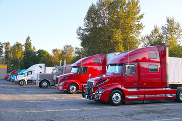 Various types of trucks in the parking lot next to the motorway. Truck stop.