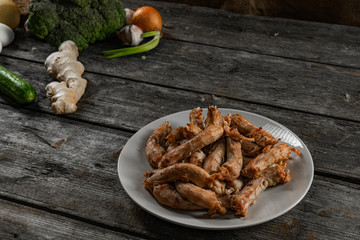 Fototapeta premium Plate of fries chicken necks and vegetables on wooden table