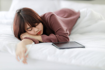Obraz na płótnie Canvas Asian woman sleeping and using tablet for working, educational, e-commerce, social media in her bed. corovavirus covid-19, stay at home, work form home concept.