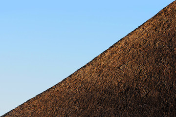 Fototapeta na wymiar Thatched roof against the blue sky, building diagonal, minimalism