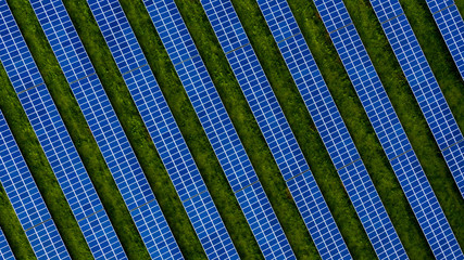 Aerial drone photo of a photovoltaic solar cell farm. Dark blue solar panels against a contrasting...