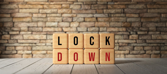 Fototapeta na wymiar wooden cubes with text LOCKDOWN in front of a brick wall on wooden floor
