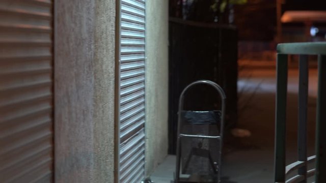 Empty night city street, roller shutters at closed shop door.