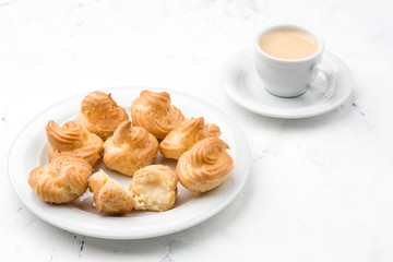 Homemade profiteroles with cream and coffee. Close-up.