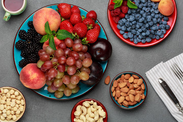 Seasonal fruits and nuts on concrete table, fresh ingredients for lunch. Healthy food concept. Top view.