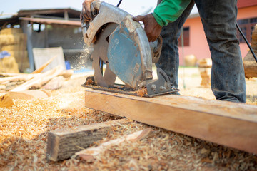 Men use electric saws to cut stump into planks.