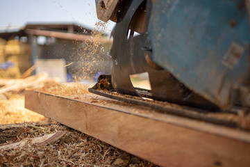 Men use electric saws to cut stump into planks.