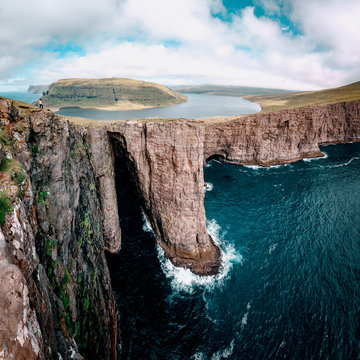 Sorvagsvatn lake over the Ocean, Vagar, Faroe Islands. Tourist girl on the cliff (MR)