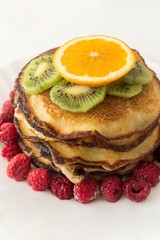Top view of pancakes with orange, kiwi and raspberries.
