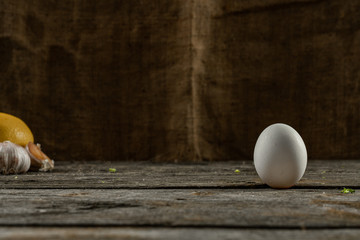 White chicken egg stands on the wooden table with copyspace