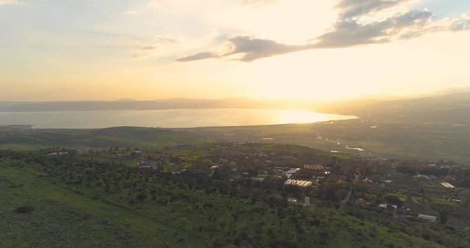 Aerial shot at sunset above Golan Heights and Taiberia in North of Israel. Open fields with orange green landscapes and mountains above Galilee sea or Kinnert at Jordan valley 