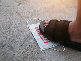 People treading on dirty used surgical face mask to protect Covid-19 on the floor. Medical waste disposal.