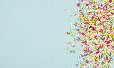 culinary pastry rainbow sprinkles are scattered on a blue background