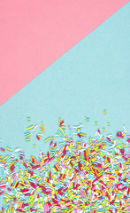 culinary pastry rainbow sprinkles are scattered on a pink and blue background