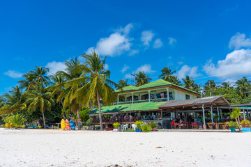 Gorgeous tropical sandy beach with palm trees, blue sky and clear water.