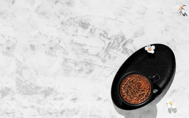 Black cup of coffee of aromatic espresso on a light gray background, top view.