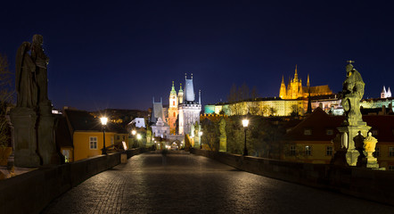 Obraz premium Night colorful Prague gothic Castle with St. Nicholas' Cathedral and Bridge Tower from Charles Bridge with its baroque Statues without People at the time of Coronavirus, Czech Republic
