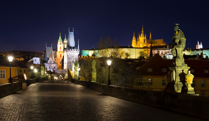 Obraz premium Night colorful Prague gothic Castle with St. Nicholas' Cathedral and Bridge Tower from Charles Bridge with its baroque Statues without People at the time of Coronavirus, Czech Republic