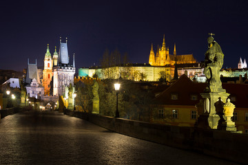 Fototapeta premium Night colorful Prague gothic Castle with St. Nicholas' Cathedral and Bridge Tower from Charles Bridge with its baroque Statues without People at the time of Coronavirus, Czech Republic