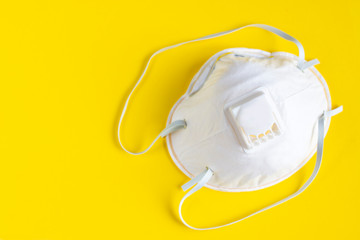 White respirator on a yellow background. Antiviral medical mask for protection against coronavirus. Prevention of the spread of virus and pandemic COVID-19.