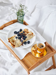 Breakfast table in the bed with filled crepes and a cup of coffee