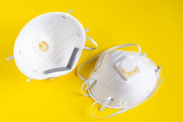 Two white respirators on a yellow background. Antiviral medical mask for protection against...