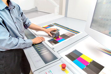 オフセット印刷において印刷物の濃度を測定する手元のアップ。カラーマネージメント、品質管理イメージ - obrazy, fototapety, plakaty