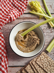  Hummus with hemp seeds served with celery stalks on a rustic wooden table