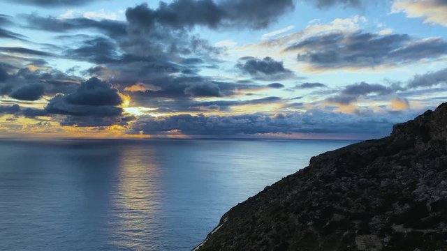 Romantic sunset over the sea with large fluffy clouds. Peaceful ocean during the golden hour