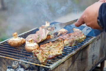 The process of cooking barbecue steaks on an open fire.