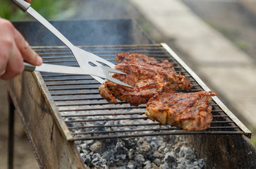 The process of cooking barbecue steaks on an open fire.