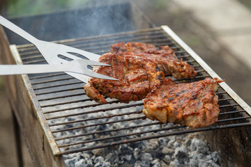 The process of cooking barbecue steaks on an open fire.