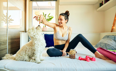 Attractive fit woman enjoying with dog at home after work out.