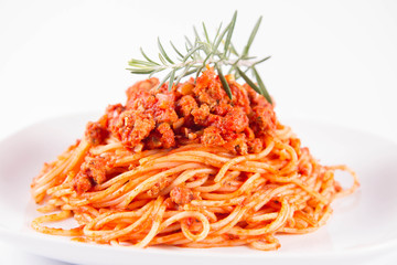 Spaghetti bolognese on a plate decorated with a rosemary twig