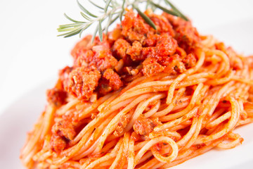 Spaghetti bolognese on a plate decorated with a rosemary twig