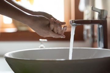 Side view close up young woman washing hands with bubble cleansing soap under tap water in washroom. Cautious girl disinfecting palms with antiseptic liquid, killing corona virus bacteria indoors.